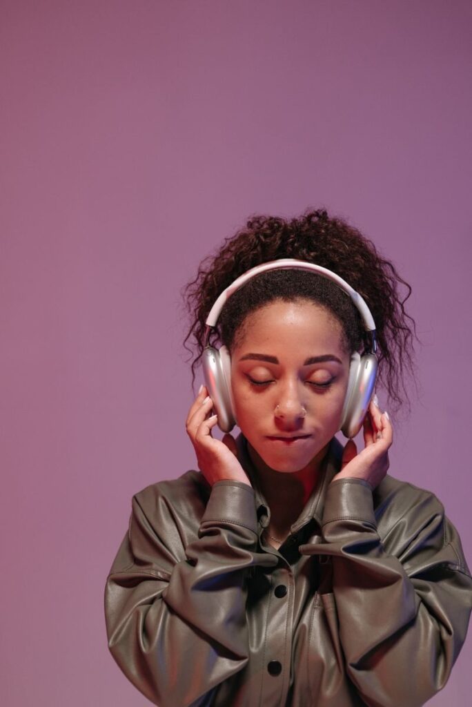 Serene portrait of a woman enjoying music with wireless headphones against a soft backdrop.