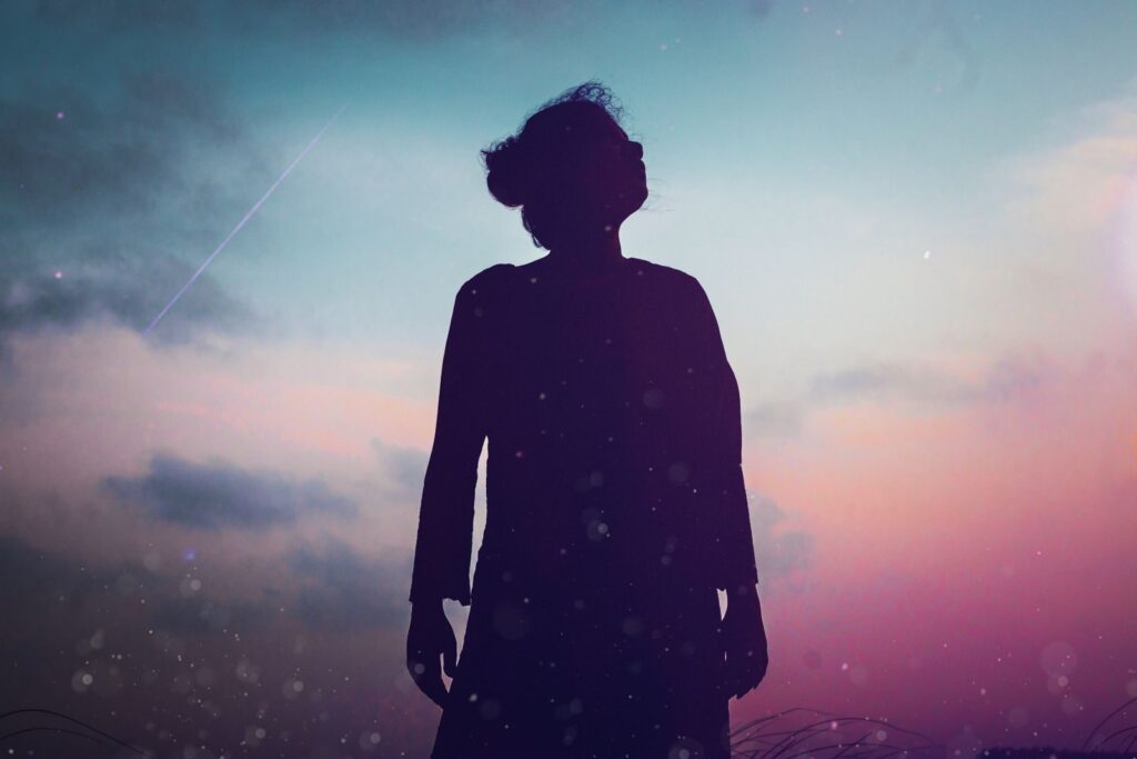 Silueta de mujer contemplando el cielo violeta al atardecer