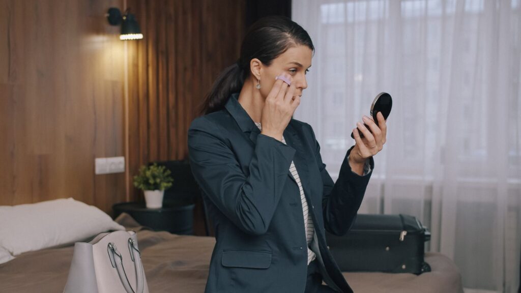 Mujer profesional repasando su imagen con un espejo antes de una reunión importante