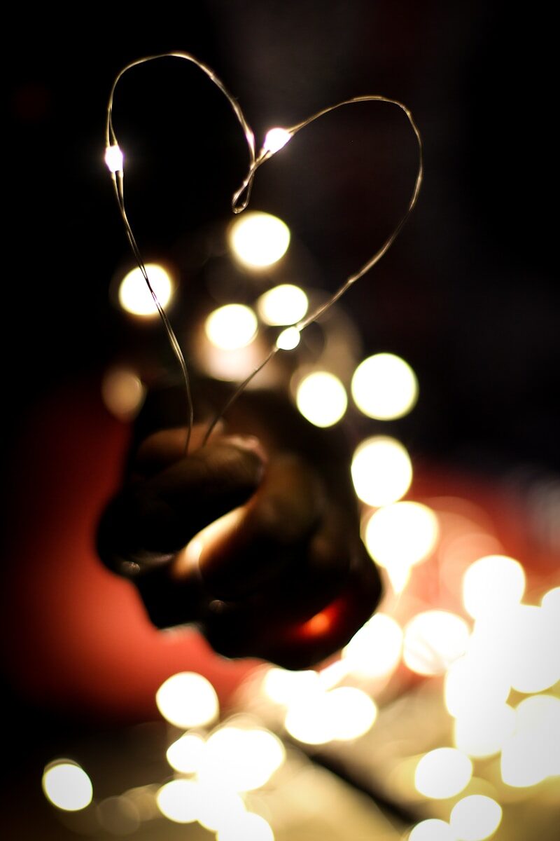 Persona sosteniendo una guirnalda de luces cálidas, simbolizando la necesidad emocional de sentirse vista