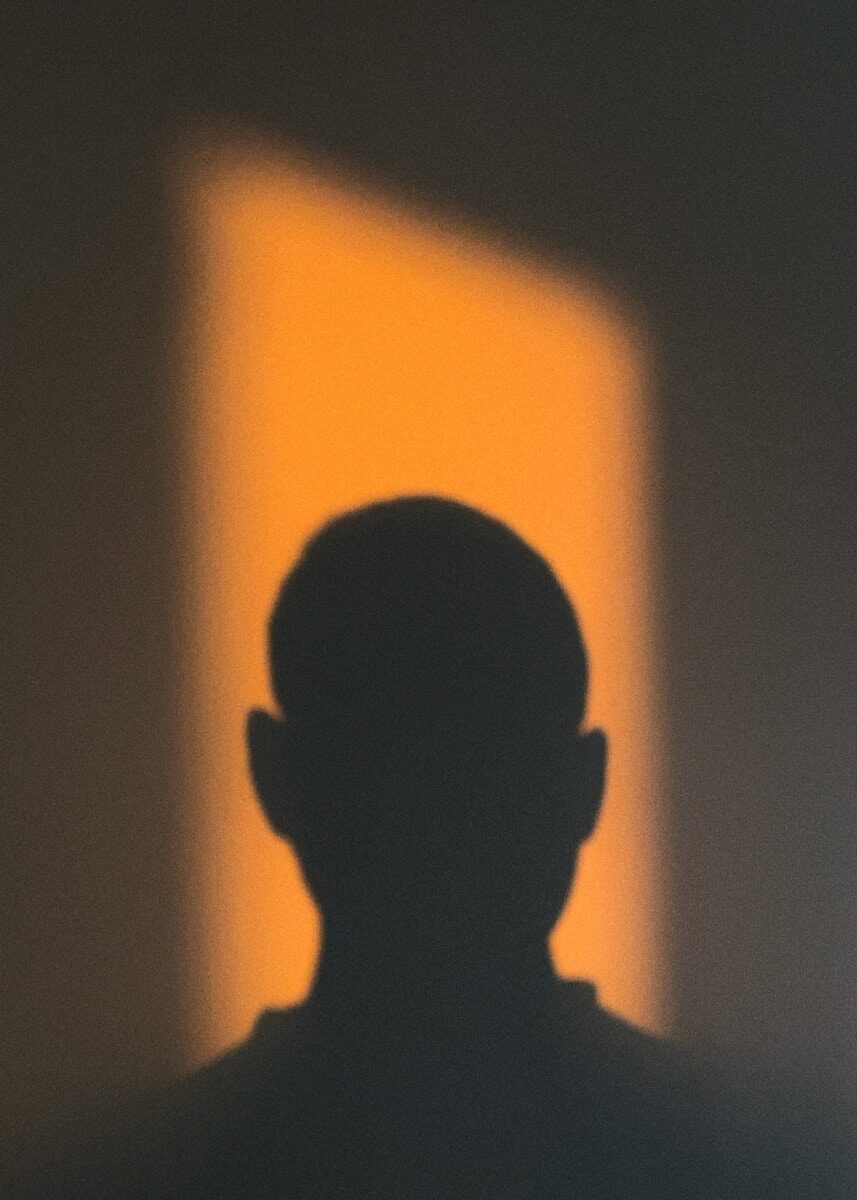 Persona iluminada por luz cálida con un lado del rostro en sombra, representando el contraste entre el brillo y la vulnerabilidad del Ascendente en Leo