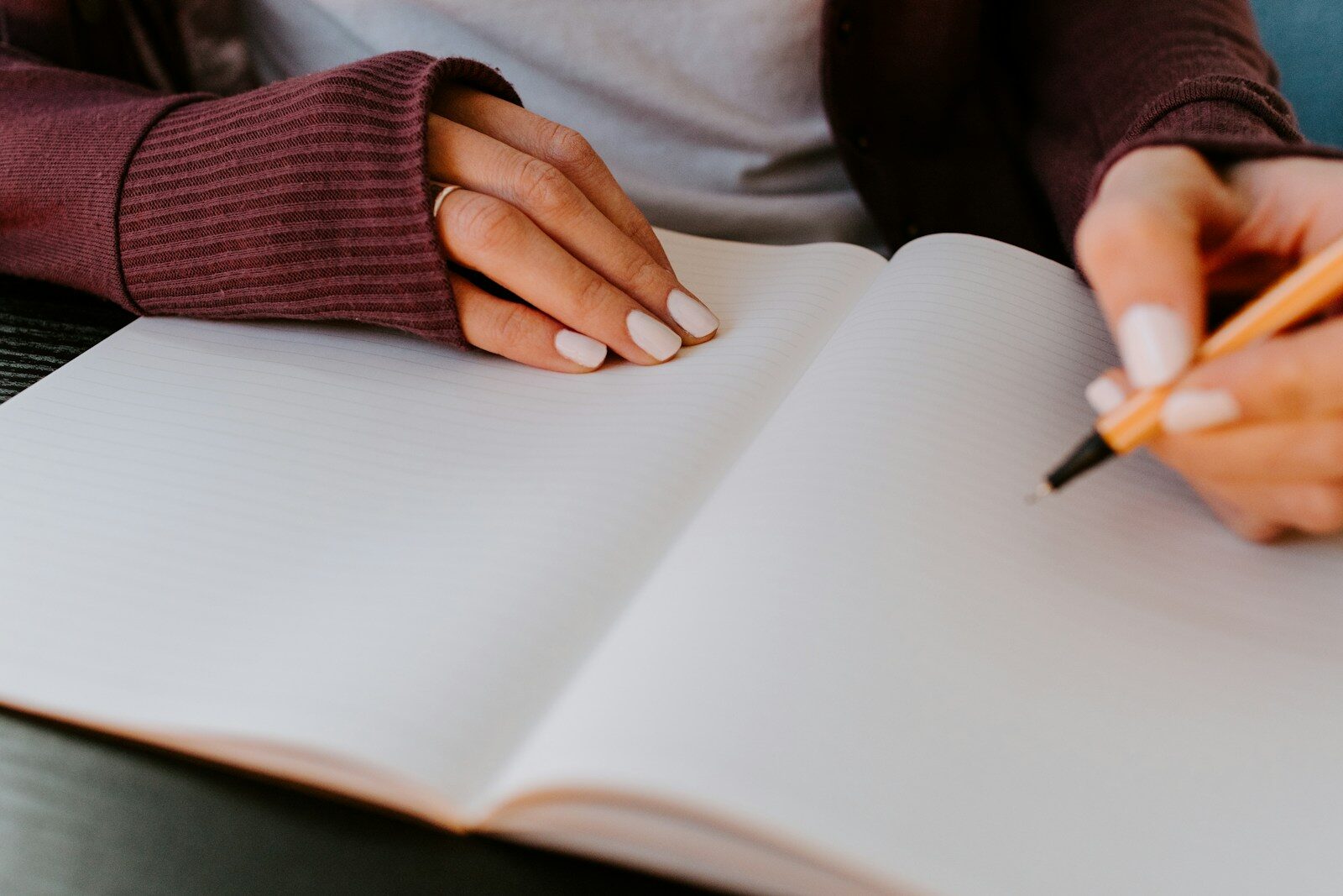 Persona escribiendo en un cuaderno junto a un ordenador, reflexionando sobre sus decisiones profesionales