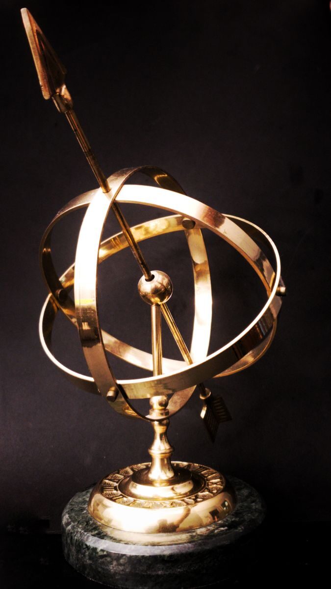 Close-up of a brass armillary sphere on a marble base, highlighting intricate metalwork and design.