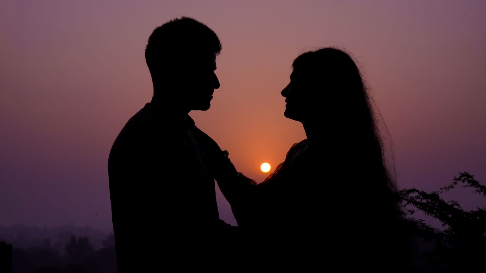 Silhouette of a couple embracing at sunset, capturing a romantic moment.