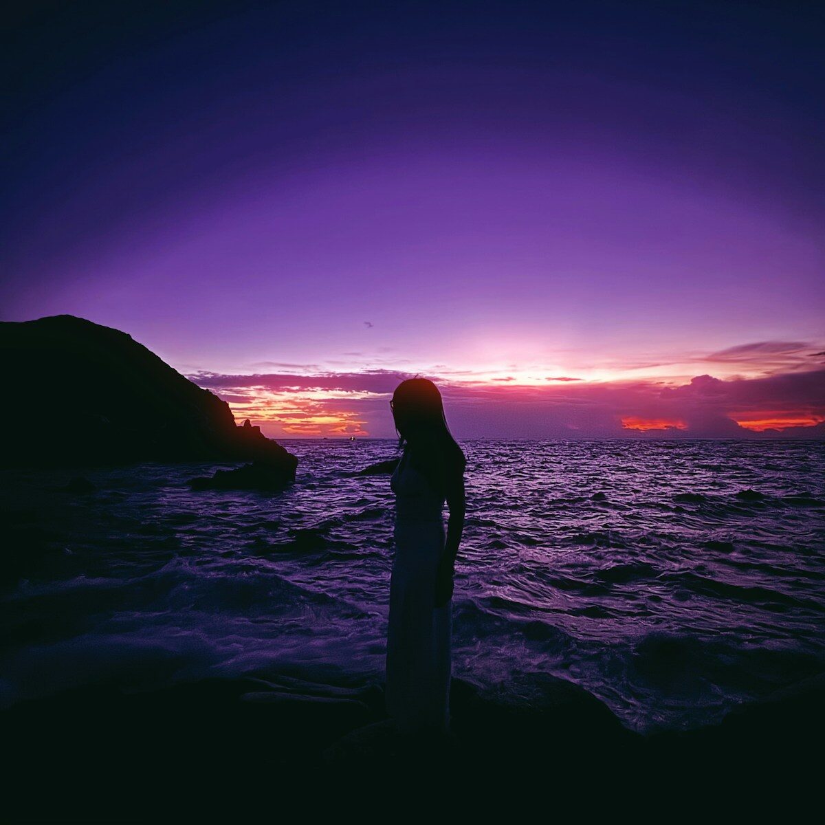 Silhouette of a woman against a vibrant purple sunset.
