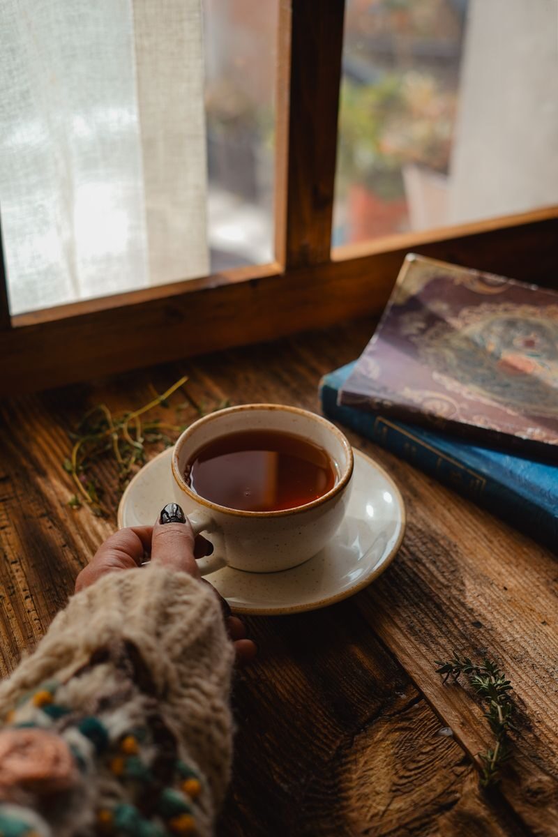Taza de té caliente sobre una mesa de madera junto a una ventana cálida, evocando la calma y seguridad de la Luna en Tauro