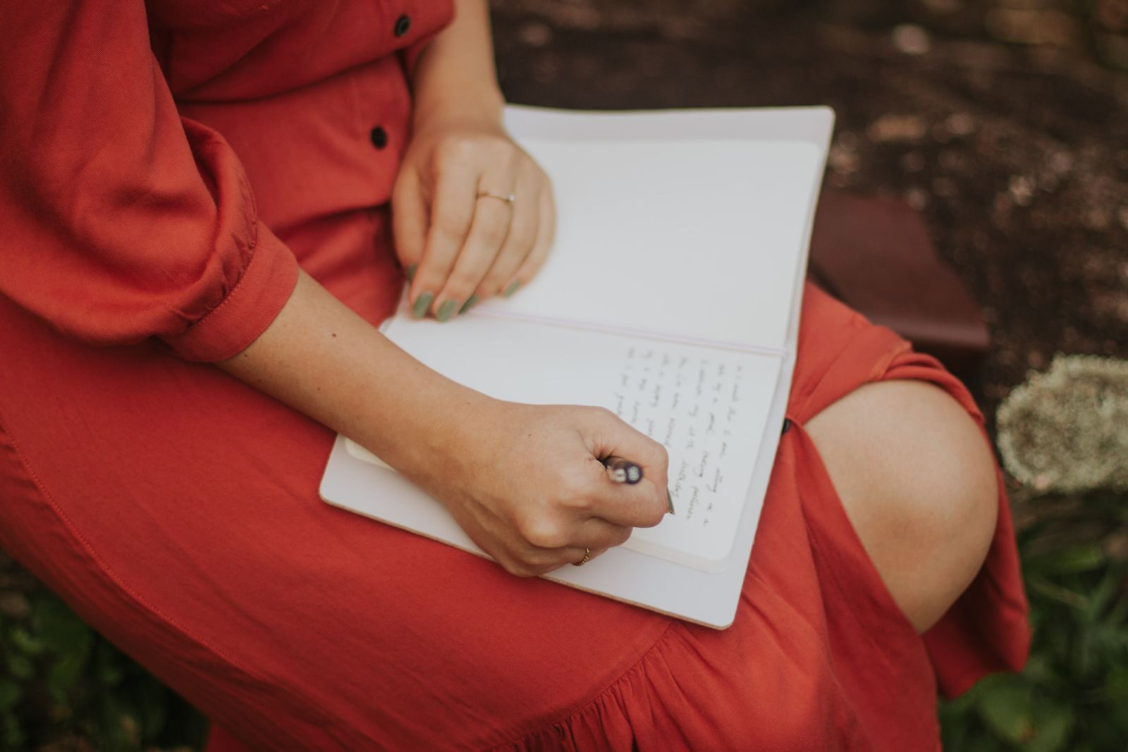 Mujer escribiendo en un diario al aire libre, representando la necesidad de poner en palabras lo que siente la Luna en Géminis