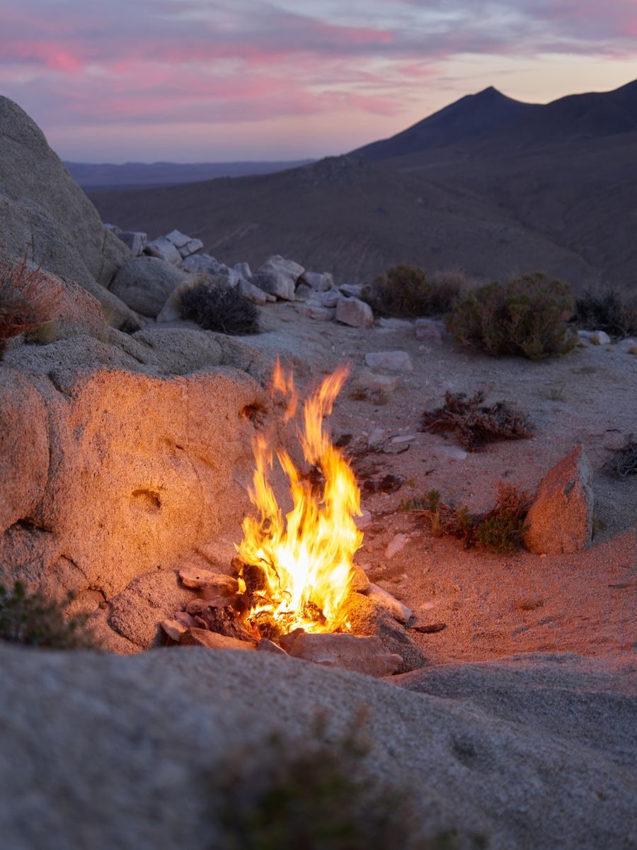 Hoguera encendida en un paisaje desértico al atardecer, simbolizando la energía de fuego de Aries