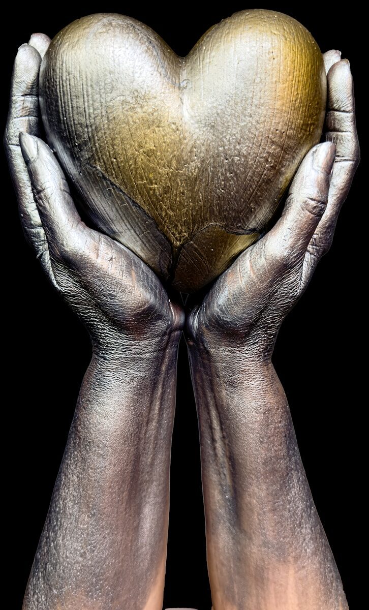 a pair of hands holding a golden heart