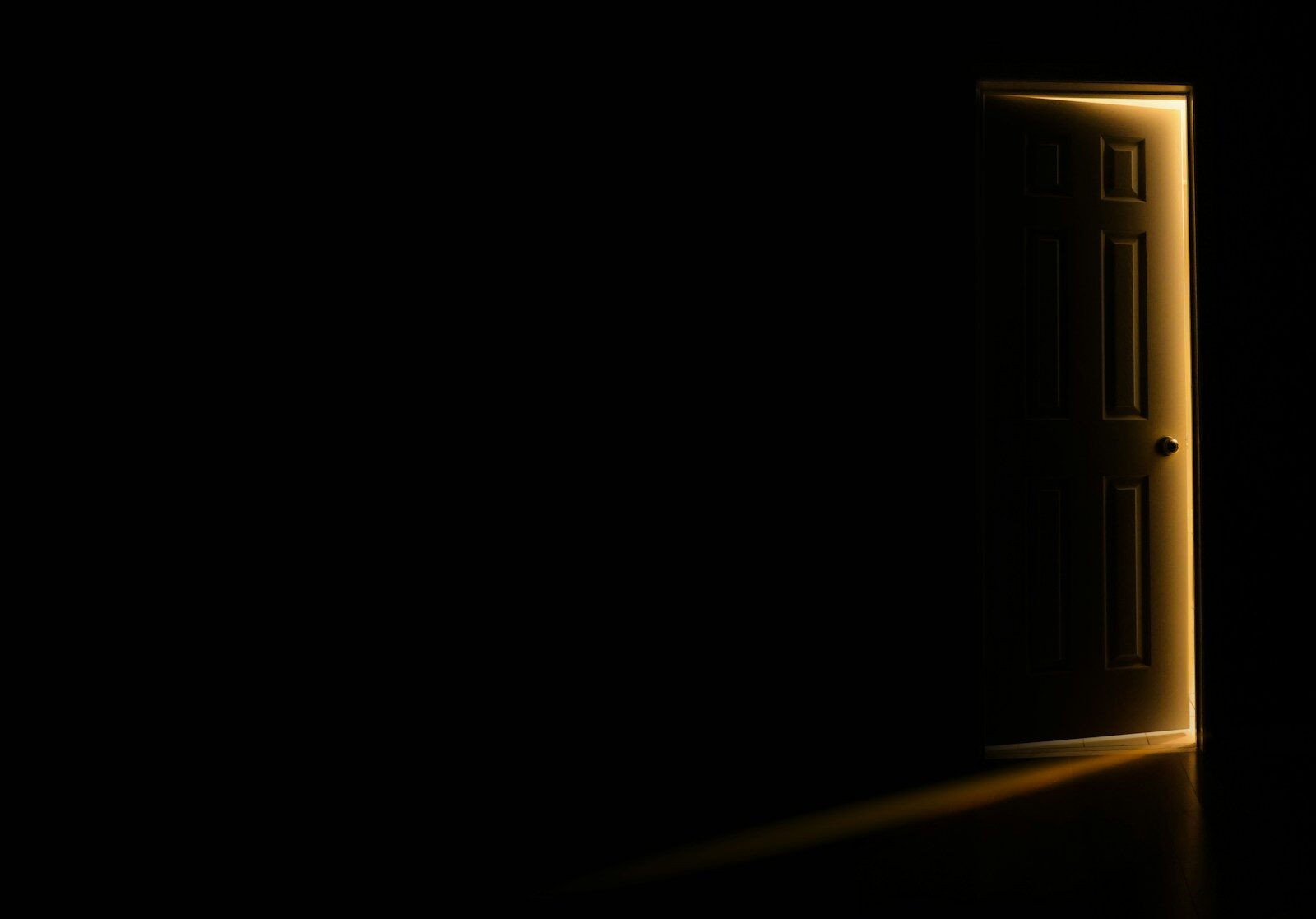 Puerta entreabierta dejando pasar la luz en una habitación oscura, simbolizando el filtro de entrada del Ascendente en Cáncer