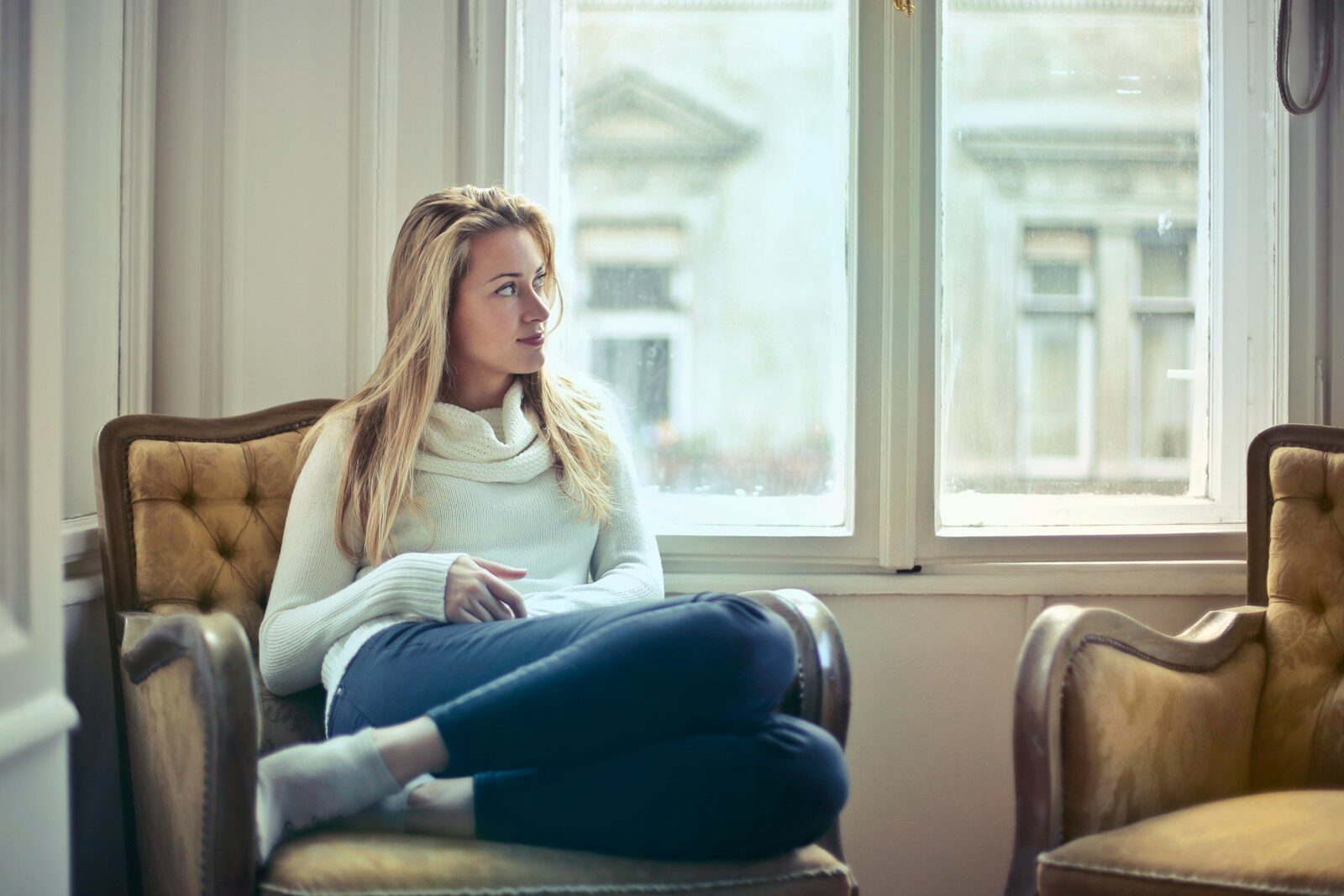 Mujer pensativa mirando por la ventana, representando la sensación de agobio al querer empezar con la inteligencia artificial