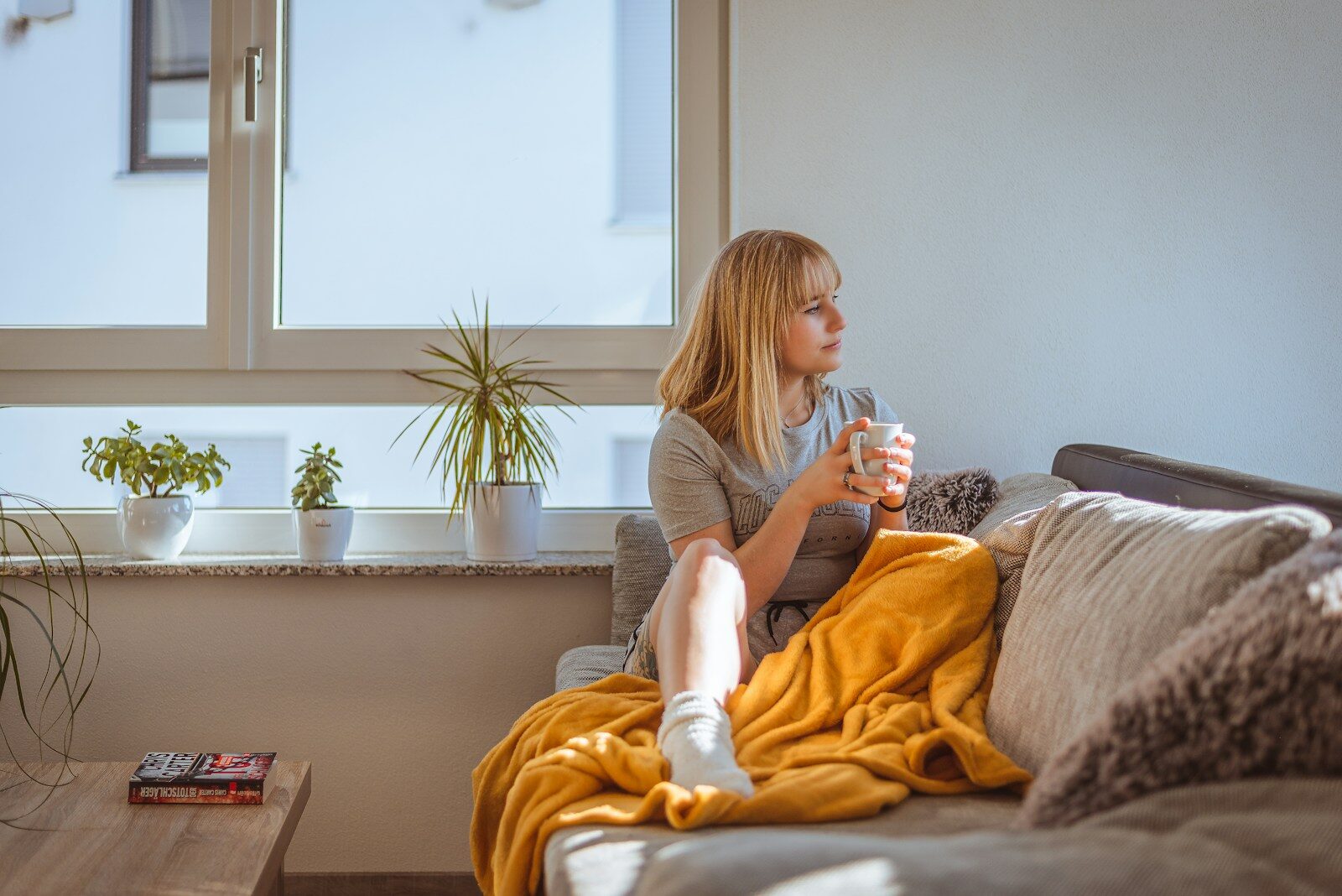 Mujer relajada tomando un té junto a la ventana, en un momento de calma para reflexionar sobre sí misma