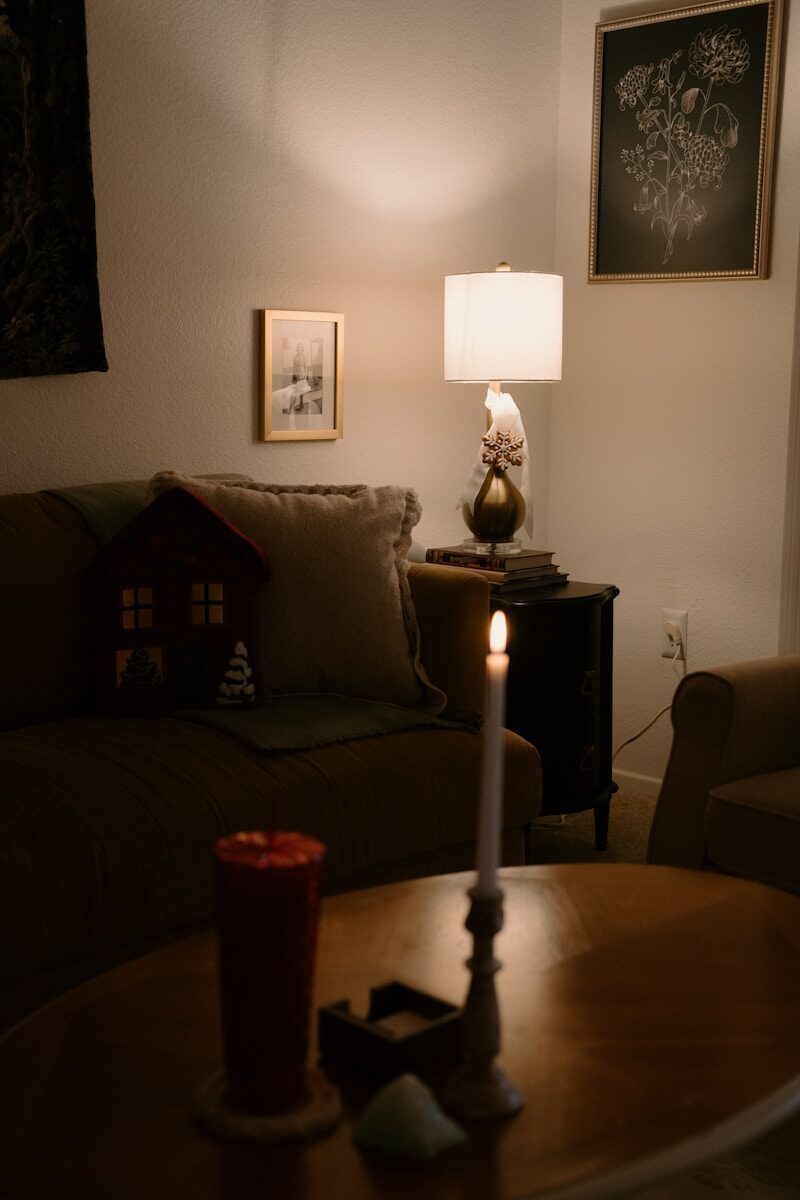 Vela encendida junto a una lámpara en una habitación acogedora, transmitiendo calidez emocional